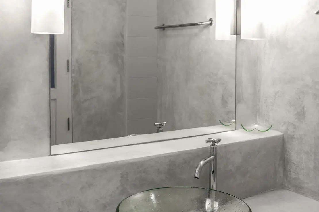 Baño con muros y superficie de microcemento en tono gris